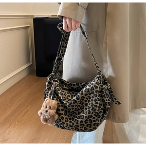 Close-up of leopard print canvas crossbody bag with a plush bear charm on a trench coat