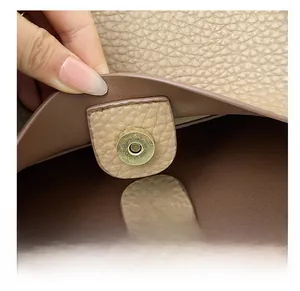 Detail shot of high-quality magnetic metal buckle on beige lychee leather tote bag