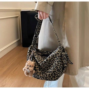 Close-up of leopard print crossbody bag with brown plush bear charm and wide strap