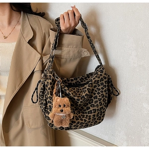 Detail of leopard print canvas crossbody bag with plush dog charm and adjustable strap