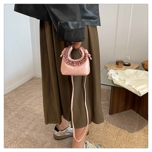 Mini pink crossbody bag with brown plaid ruffle detail worn by a model in a natural setting