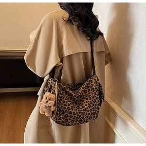 Detail of leopard print hobo bag worn by model with brown bear plush keychain accessory