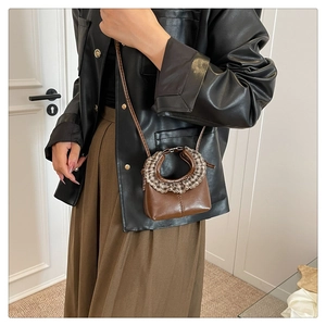 Detail of mini crossbody bag with brown leather and black and white checkered ruffle handle