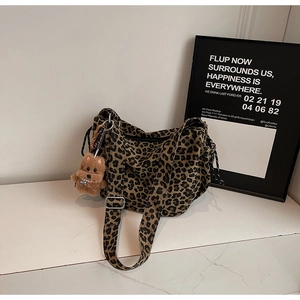 Detail of vintage leopard print canvas crossbody bag with plush puppy keychain