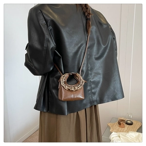 Mini caramel brown leather crossbody bag with pleated trim shown on model shoulder