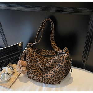 Close-up of leopard print canvas bag with adjustable strap and cute teddy bear pendant