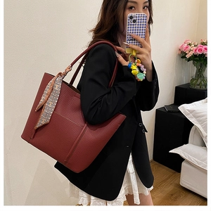 Detail of burgundy lychee grain leather tote bag with printed silk scarf wrap on handles