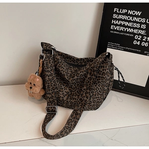 Detail of leopard print canvas crossbody bag with wide strap and cute plush dog charm