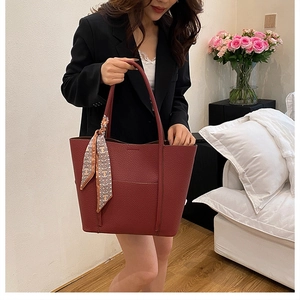 Close-up of wine red lychee leather tote bag with elegant silk scarf on handle