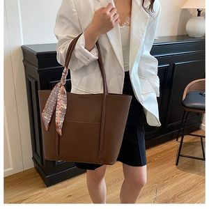Brown lychee leather tote bag with decorative silk scarf on model in white blazer