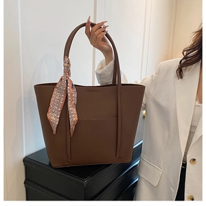 Close-up of deep brown pebbled leather tote bag with decorative geometric silk scarf