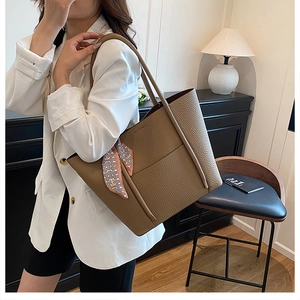 Large dark khaki lychee leather tote bag with a geometric scarf on handle shown on a model