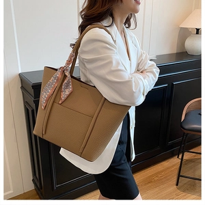 Brown litchi grain leather tote bag with elegant silk scarf on a female model