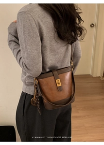 Détail d'un sac seau rétro en cuir marron avec fermoir tournant doré et charms décoratifs