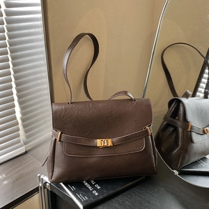Deep brown vintage tote bag with gold metal buckle and leather texture in natural light