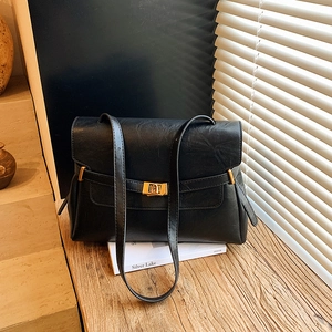Large black vintage leather tote bag with gold twist lock on a warm wooden background