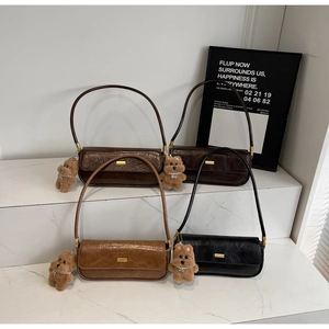 Detail view of four textured baguette bags in brown and black with plush puppy charms