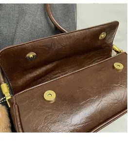 Detail view of double gold magnetic buckles on vintage brown leather shoulder bag