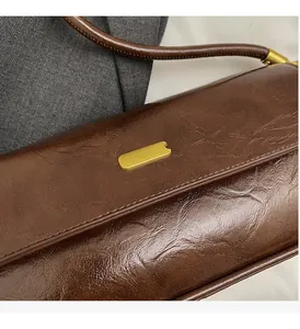 Macro detail of dark brown oil wax leather and gold metal hardware on shoulder bag