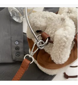Detail of silver metallic hardware hook and textured plush beige faux fur on bucket bag