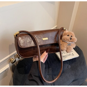 Detail view of brown faux leather shoulder bag with golden hardware and plush dog charm