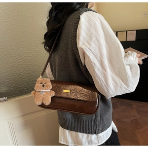 Brown leather underarm bag with embossed flap detail and cute teddy bear charm