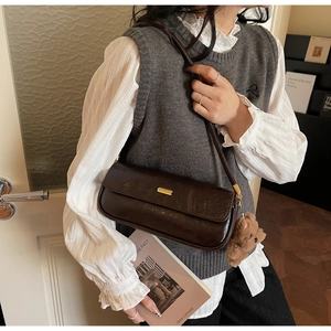Deep brown baguette shoulder bag featuring a gold buckle and cute plush bear charm detail