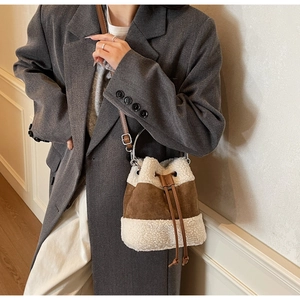 Detail of contrast stitching on plush sherpa and suede bucket bag with drawstring