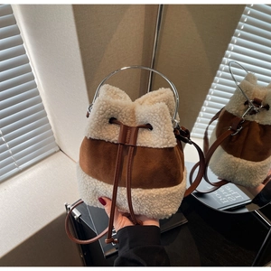 Detail of plush sherpa bucket bag with brown suede patchwork and metal ring handle