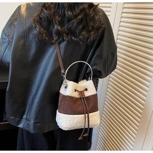 Detail view of plush shearling bucket bag with silver ring handle on model shoulder