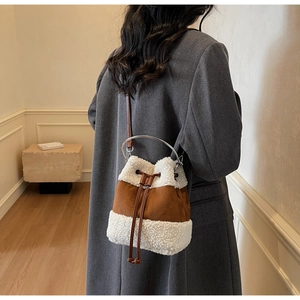Detail of plush bucket bag featuring contrast shearling texture and metal ring handle