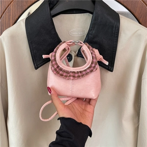 Pink mini crossbody bag with plaid ruffle trim and silver ring buckle on beige coat