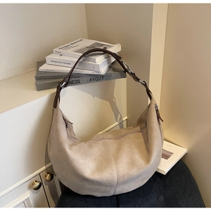Detail of hobo bag showing beige suede texture, dark brown strap and silver metal hardware