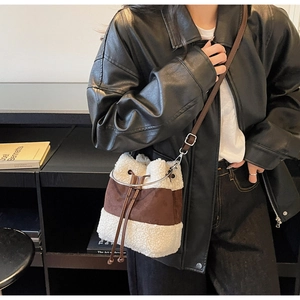 Macro detail of plush faux fur bucket bag with brown suede stitching and metal ring handle