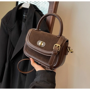 Dettaglio di una piccola borsa quadrata marrone scuro con chiusura in metallo e texture