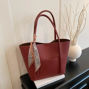 Elegant burgundy lychee leather tote bag with silk scarf on a minimalist setup