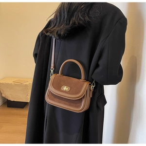 Dettaglio della borsa in pelle marrone con chiusura girevole in metallo vintage e texture in pelle