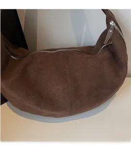 Detail of dark brown suede hobo bag with vintage texture and silver zipper closure