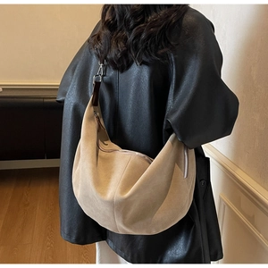 Detail of khaki suede hobo bag showing soft texture and contrast dark leather shoulder strap