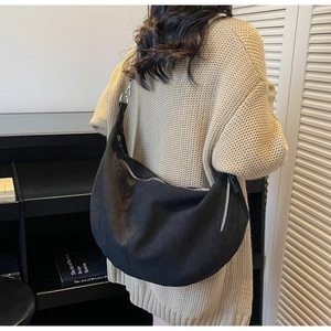 Model wearing large black crescent hobo bag showing size scale and drape on shoulder