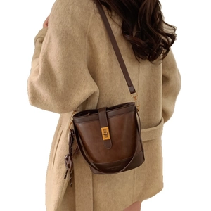 Sac seau vintage en cuir marron avec fermoir doré et bandoulière porté par un mannequin