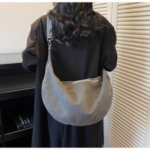 Close-up of gray suede crescent bag featuring silver zipper and minimalist design