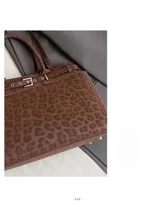 Detailed close-up of dark brown leopard print handbag with gold buckle and suede texture