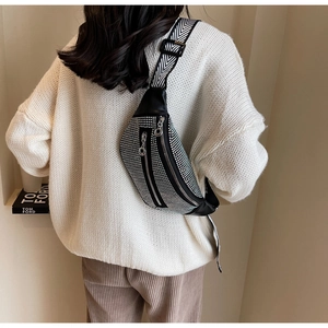 Close-up of black rhinestone waist bag with stylish herringbone wide strap on model
