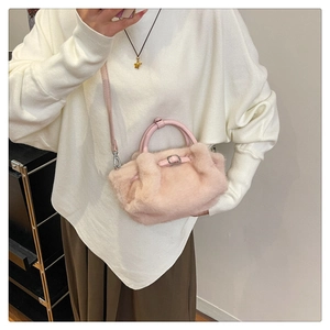 Gros plan détaillé d'un sac à bandoulière en fausse fourrure rose avec poignées en cuir