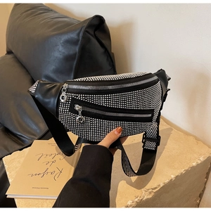 Detail of black crossbody waist bag with silver stud accents and striped strap