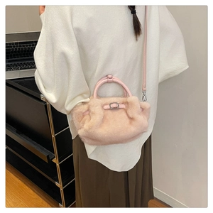 Détail d'un sac à main en fausse fourrure rose clair avec poignée ronde et bandoulière