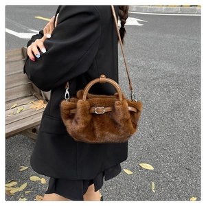 Détail du sac à main en peluche marron foncé avec lanières en cuir dans un décor d'automne