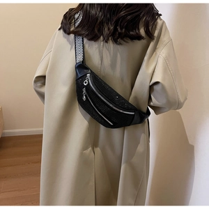 Detail of black rhinestone chest bag with a wide geometric strap on a beige trench coat