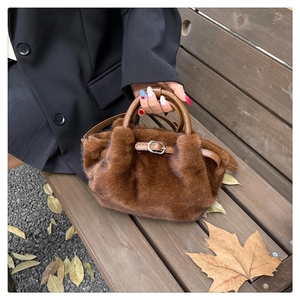 Détail du sac à main en peluche marron avec lanières en cuir sur banc d'automne